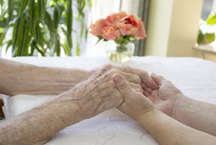 Senior and Caregiver Holding Hands in a Retirement Community