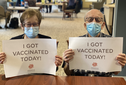 senior couple holding vaccination signs